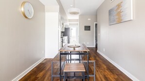 Una cocina moderna con una mesa y banco de madera, un reloj en la pared y un letrero en una pizarra.