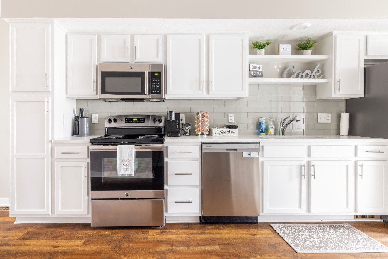 A modern kitchen with white cabinets, stainless steel appliances, a coffee bar, and a dishwasher.