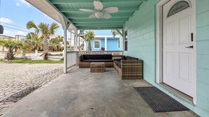 A covered porch with a ceiling fan, wicker furniture, and a white door. - Amazing Home on Main St - Walk to the Beach (North Myrtle Beach)