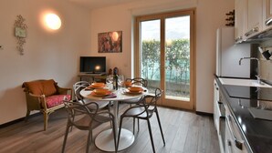 A modern kitchen with a dining area, a television, and a large window with a view of greenery. - Olmo Garden Apartment by Interhome (Valtellina)