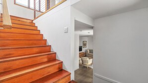 Un escalier en bois mène à un espace de vie comprenant un canapé et un téléviseur.
