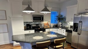 A modern kitchen with a central island, stainless steel appliances, and pendant lighting.
