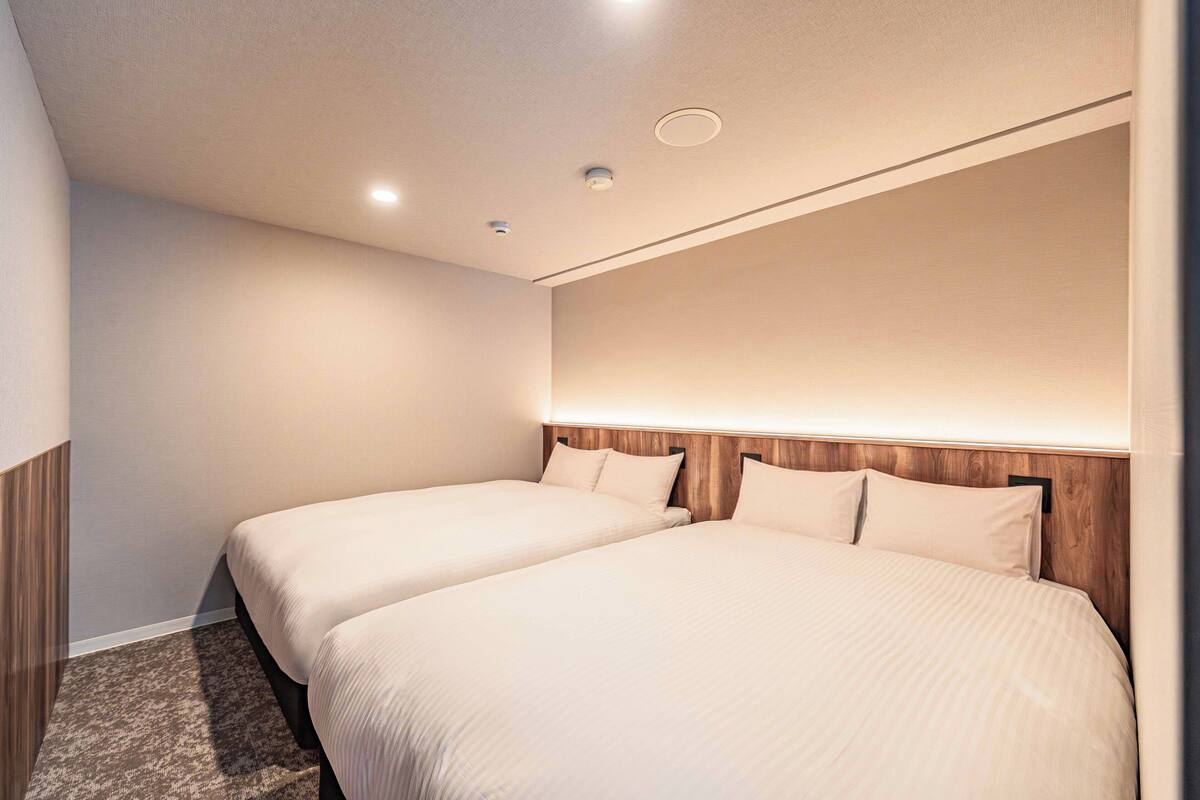 Habitación de hotel con dos camas, cabecera de madera y piso alfombrado.