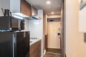 A compact kitchen with a microwave, stove, and cabinets. - Apartment Hotel 11 Namba-Minami Ebisucho (Osaka)