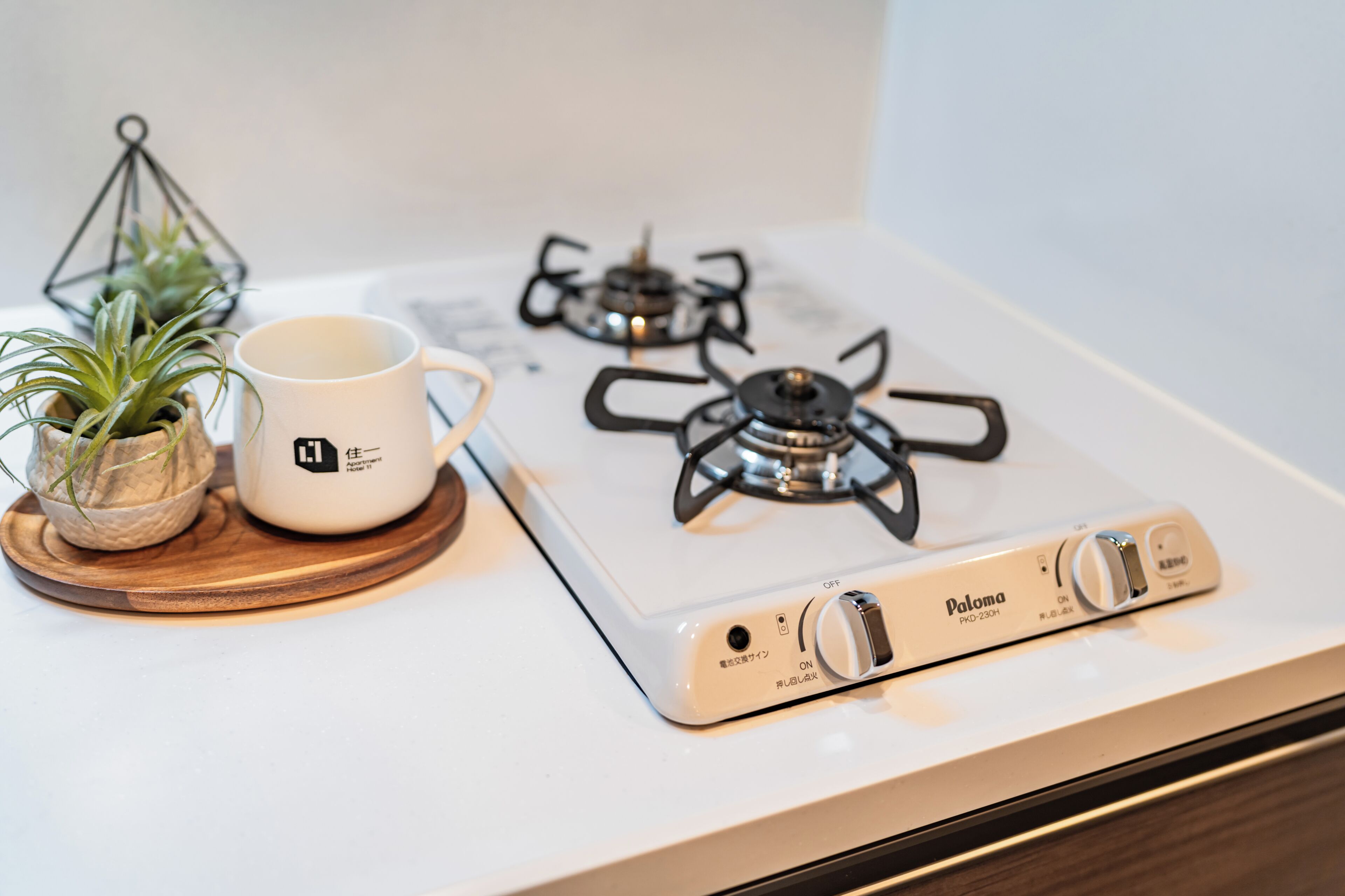 A kitchen with a white stove, a white mug, and a small potted plant on a wooden tray.