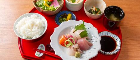 A tray with sushi, rice, and various side dishes.