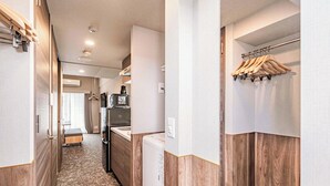 A narrow hallway with wooden paneling, a white refrigerator, a coffee maker, and a hanging clothes rack.