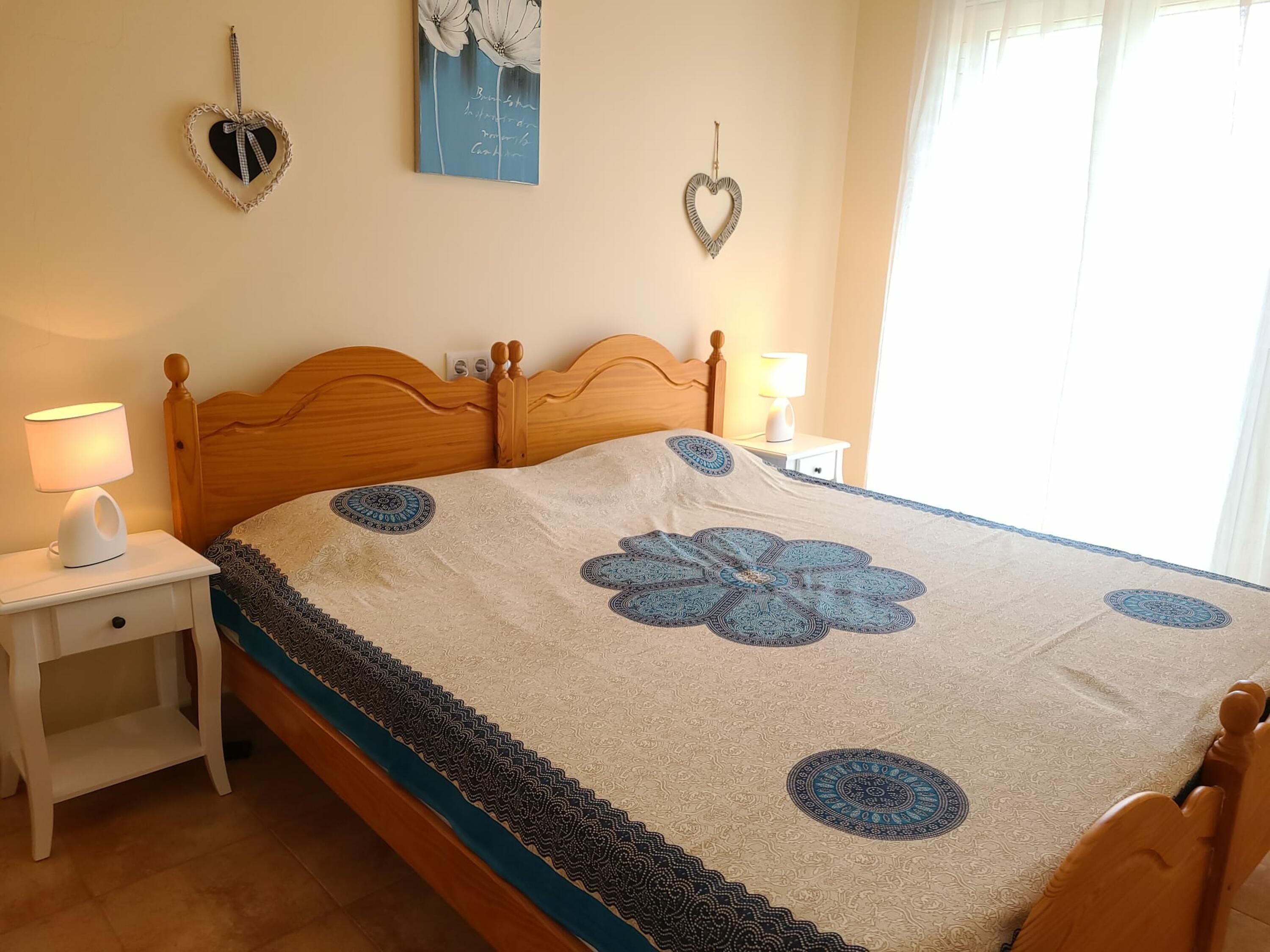 Une chambre à coucher avec un lit en bois, une table de chevet avec une lampe et des œuvres d’art décoratives accrochées au mur.