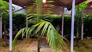 Un pavillon abrité, orné d’un logo, de palmiers et d’un escalier menant à un bâtiment.