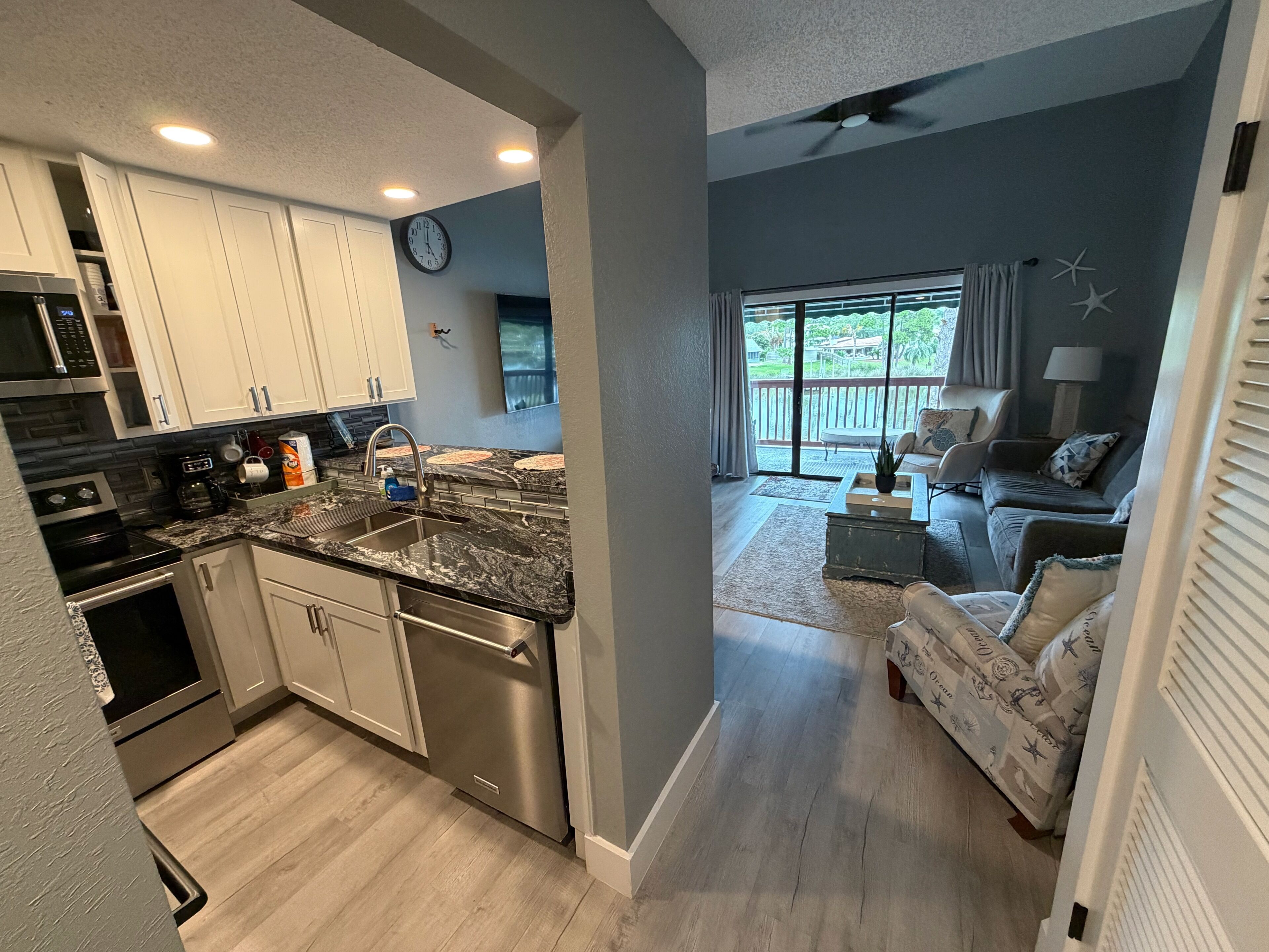 A modern kitchen with stainless steel appliances, a granite countertop, and a dining area with a view of the outdoors.