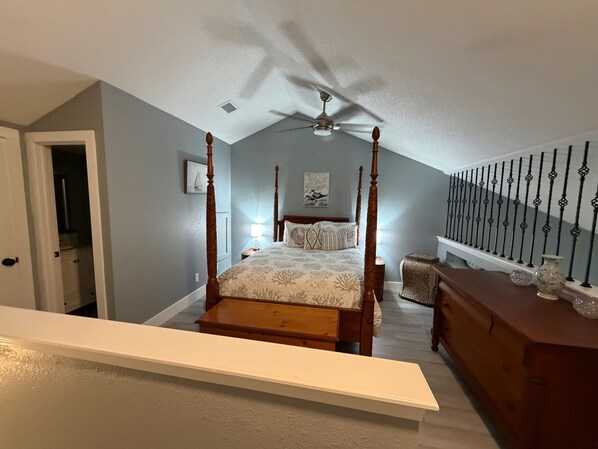 A bedroom with a four-poster bed, a ceiling fan, a nightstand, and a dresser.