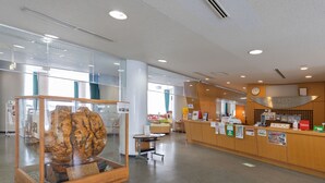 A reception area with a wooden reception desk, a glass display case with a rock, and a wall-mounted clock. - Tabist Heilsam Kurikoma Cottage (Kurihara)