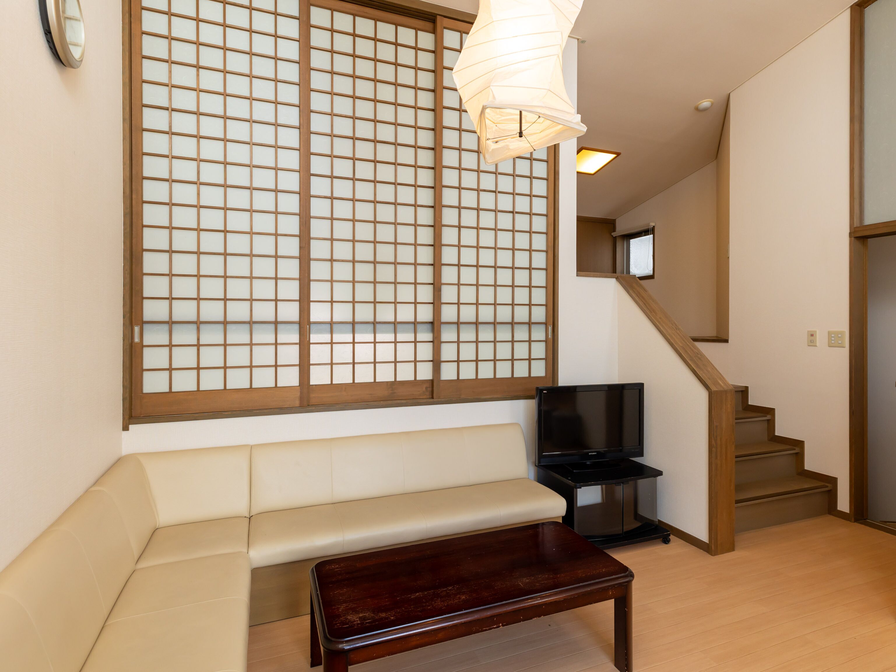 A living room with a sofa, a wooden coffee table, a TV, and a sliding door with a grid pattern.