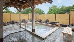 A traditional Japanese onsen with a wooden bath, stone steps, and a bamboo fence. - Tabist Heilsam Kurikoma Cottage (Kurihara)