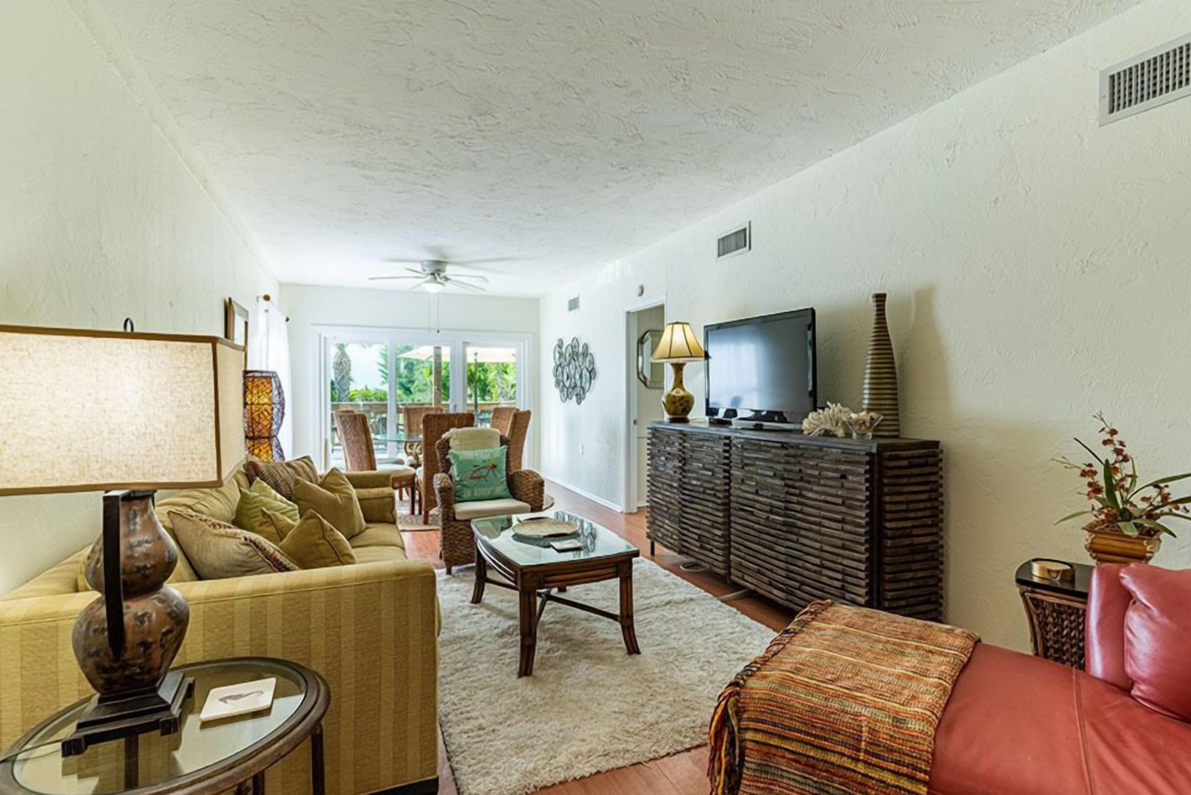 A living room with a sofa, armchairs, a coffee table, a television, and a cabinet.