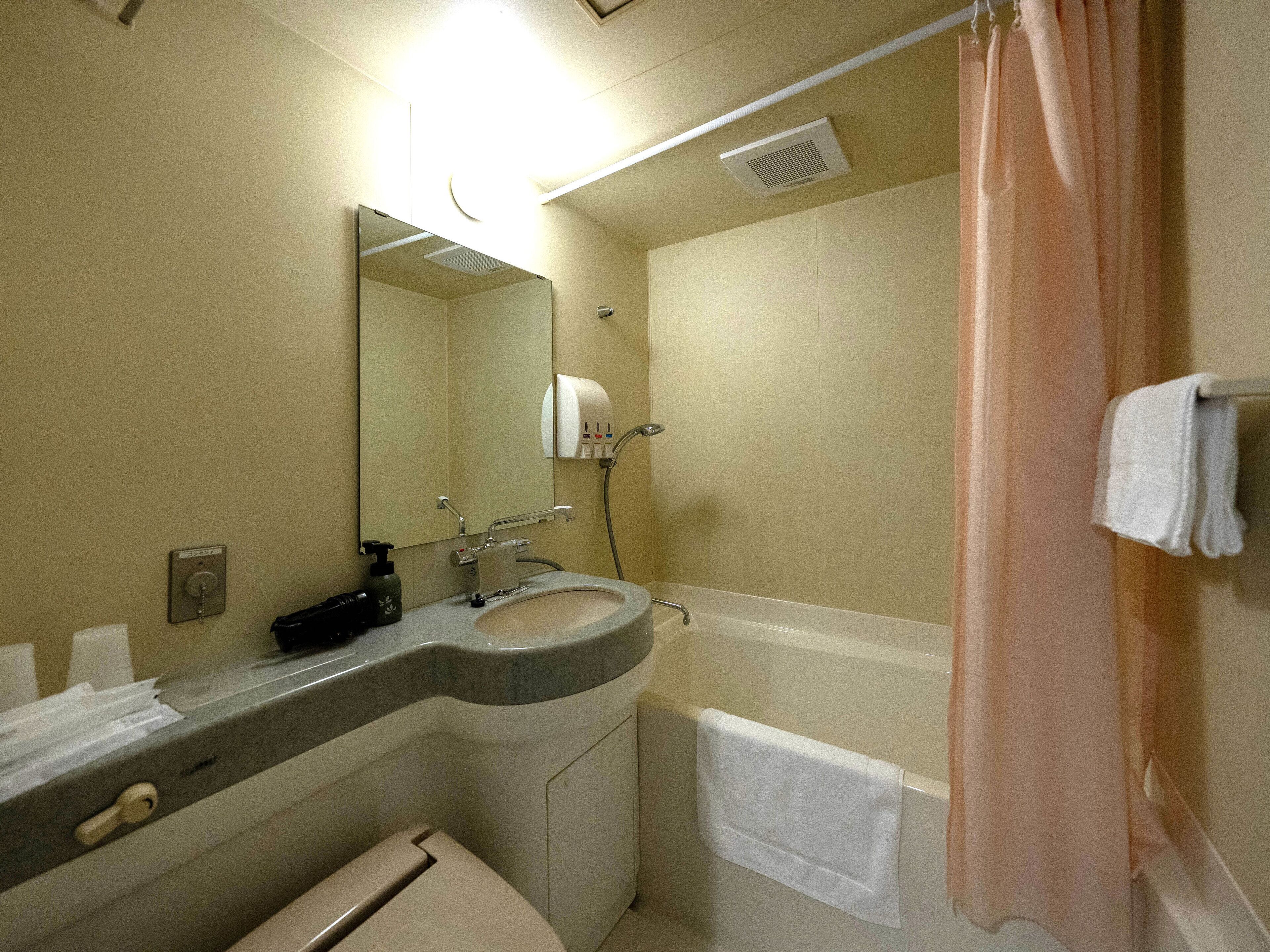 A bathroom with a sink, mirror, towel rack, and shower curtain.