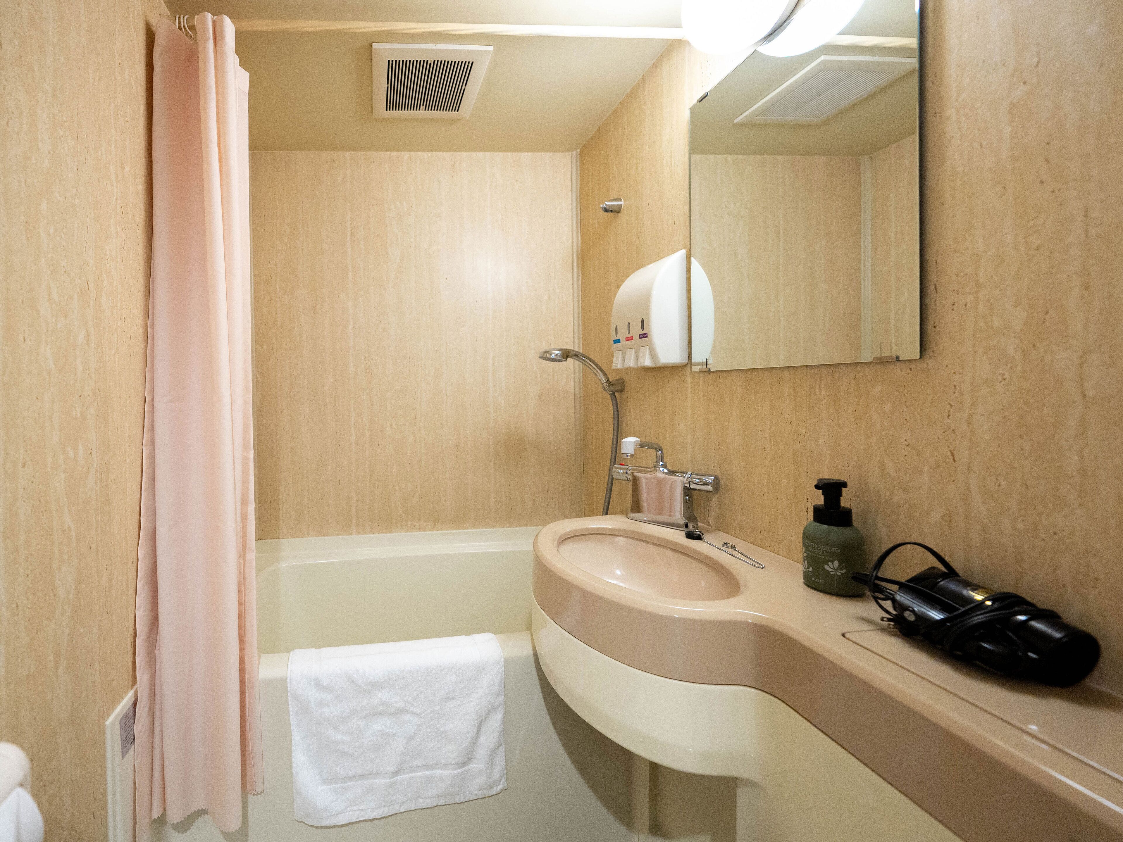 A bathroom with a bathtub, a sink, a mirror, a towel, and a shower curtain.
