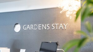 A reception desk with a sign reading "GARDENS STAY" and a globe decoration. - GARDENS STAY (Sapporo)