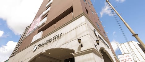 A tall building with a sign reading "GARDENS STAY" at the entrance.