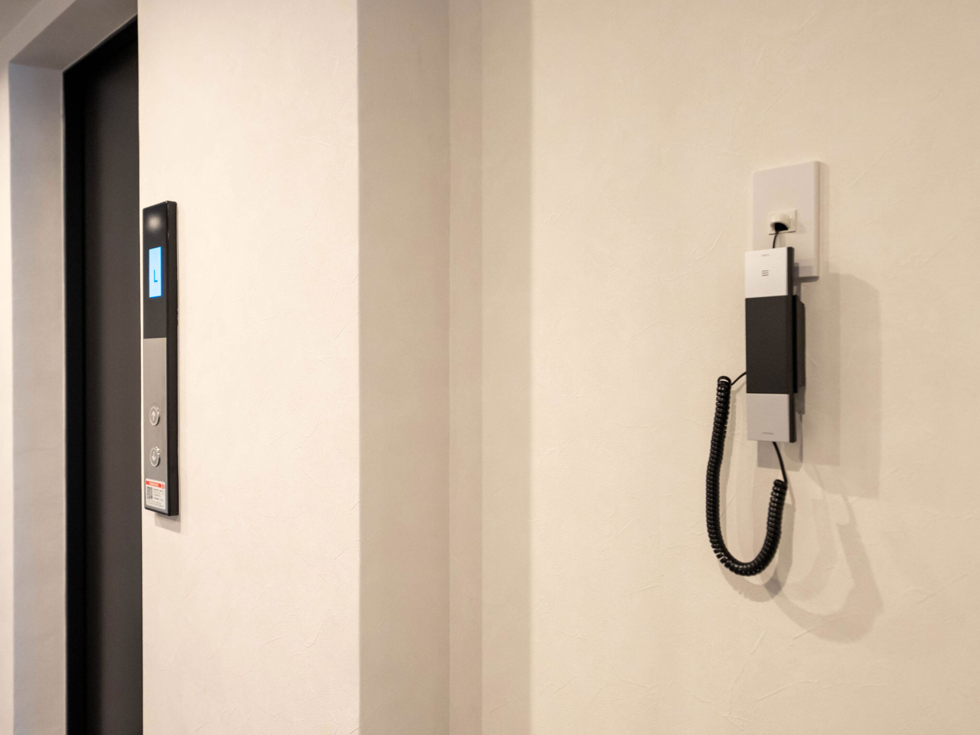 A wall-mounted telephone and a control panel with a digital display.