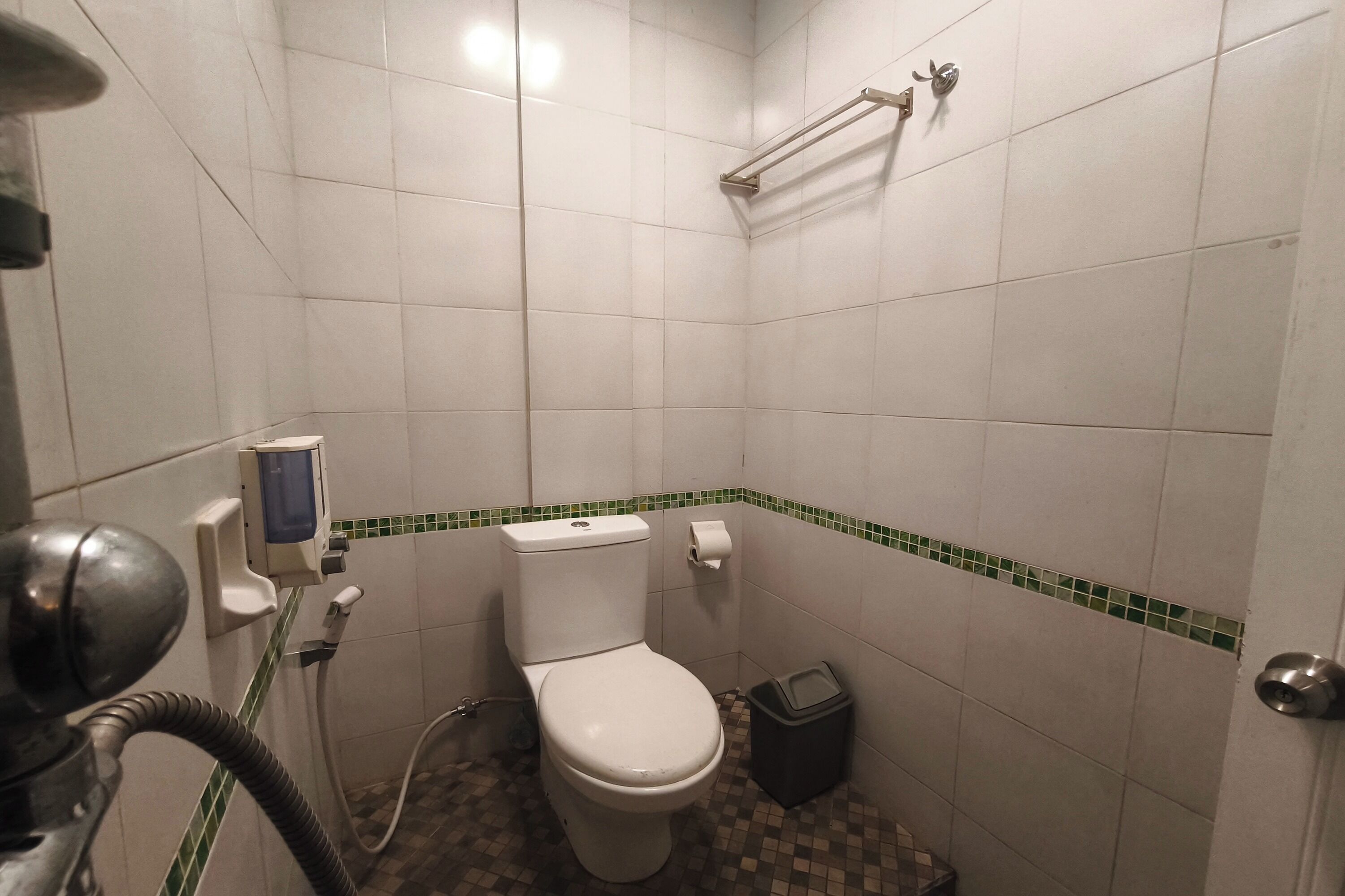 A small bathroom with a toilet, a trash bin, a towel rack, and a hand dryer.