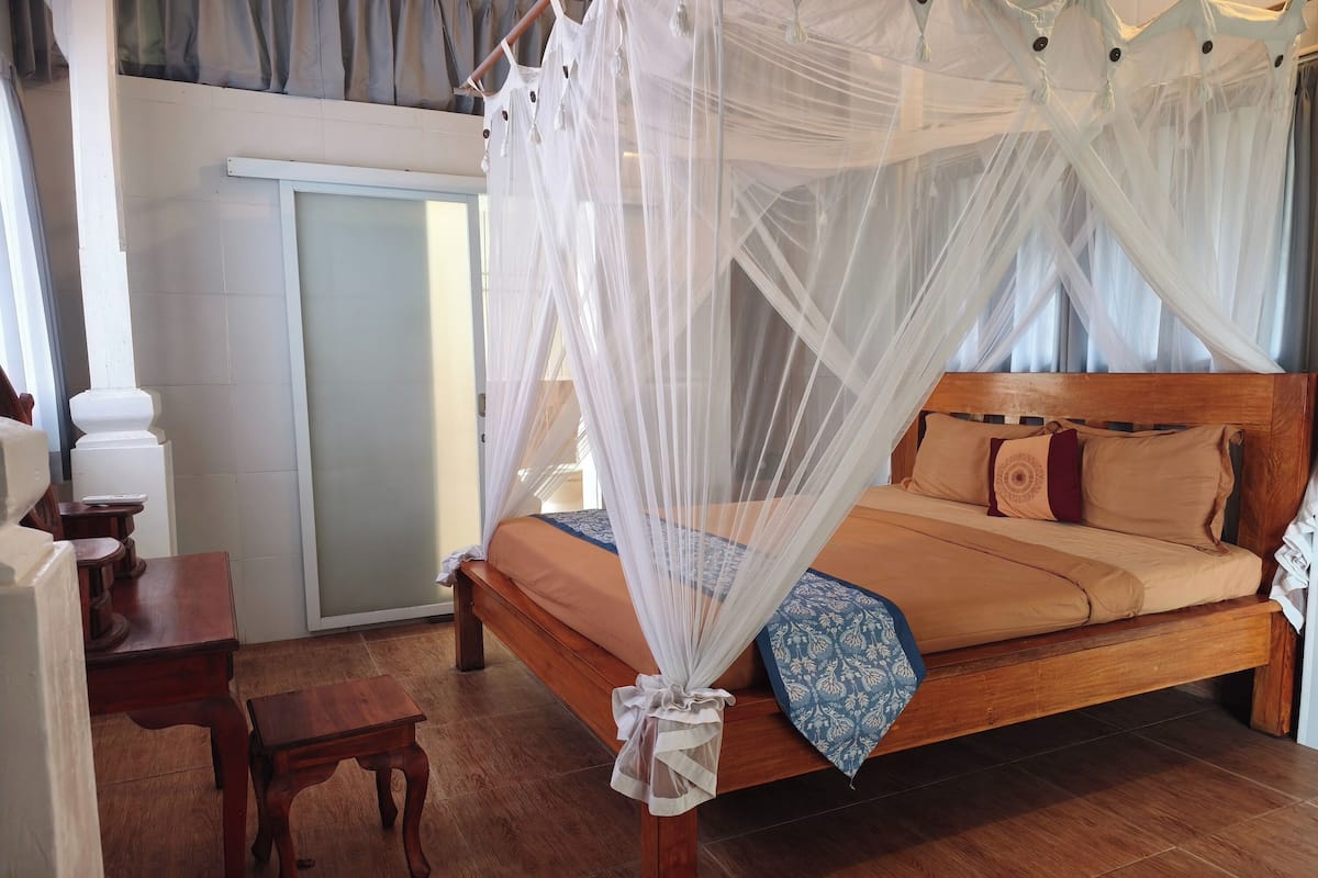 Un dormitorio con cama de madera, una mesita de noche y dosel.