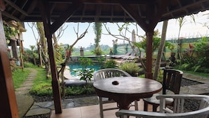 Un patio techado con piscina, sendero de piedra y zona de estar al aire libre.