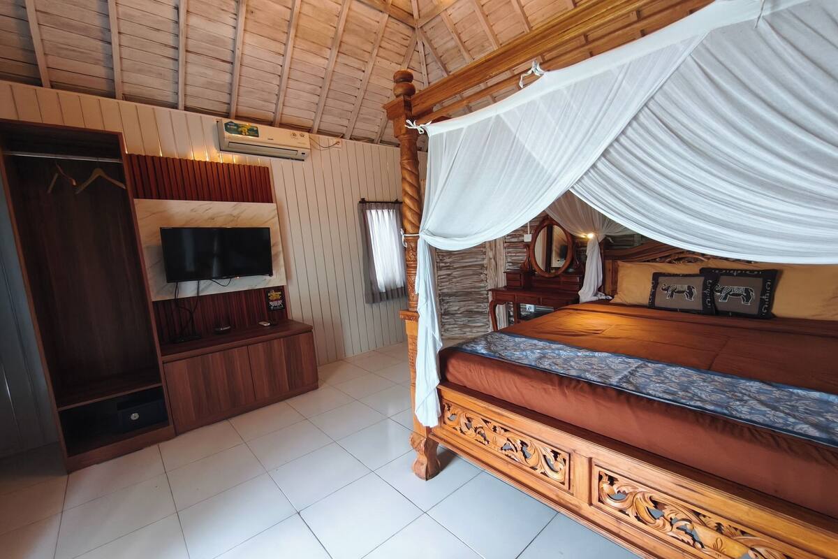 Una habitación con cama con dosel, televisor, armario y espejo.