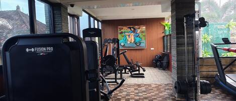A gym with various exercise equipment, a checkered floor, and a mural on the wall.