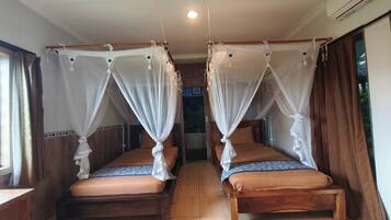 Ein Zimmer mit zwei hölzernen Betten, jeweils mit Baldachin.