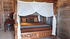 Una cama con dosel de madera, un mesita de noche de madera y un espejo.