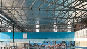 An indoor swimming pool with a blue and white checkered floor, a mural of an octopus, and a metal roof structure. - Tecco Elite Serviced Apartments (Quyet Thang)