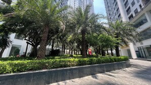 A modern urban plaza with tall buildings, palm trees, and a paved walkway. - Tecco Elite Serviced Apartments (Quyet Thang)