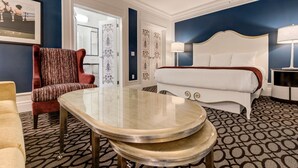 Una habitación de hotel con una cama, una silla roja, una mesa y una alfombra estampada.