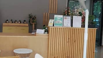 Un área de recepción con un escritorio de madera, un cartel que dice "CASA COCO Residence" y un limpiador a vapor.