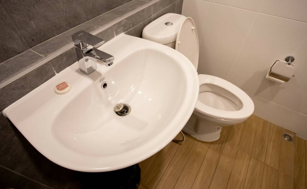 Un bagno con un lavandino bianco, un water e un portasapone.