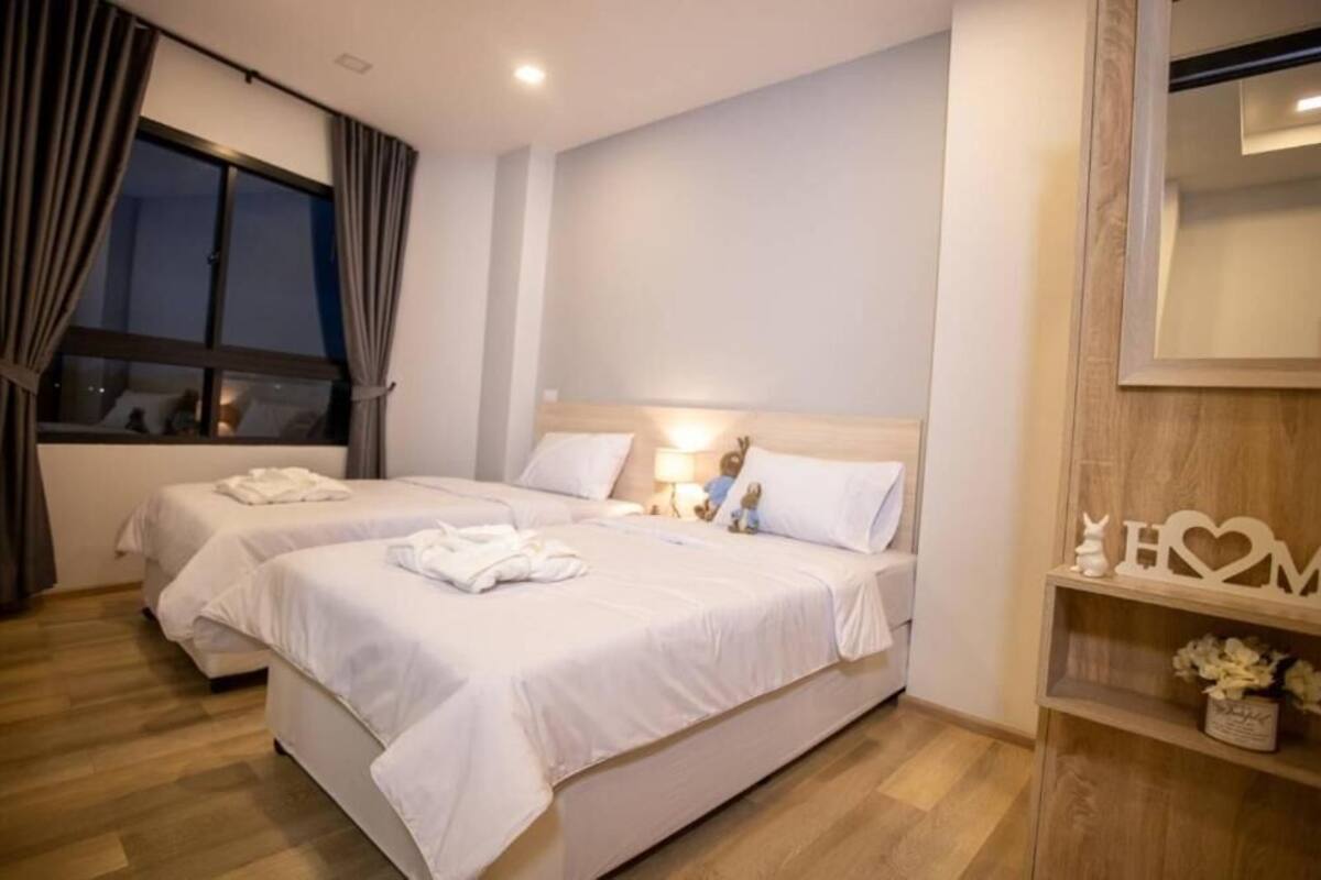 Habitación de hotel con dos camas, un cabecero de madera, una mesita de noche con lámpara y un espejo en la pared.