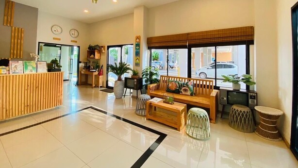 A modern hotel lobby with a reception desk, seating area, and large windows offering a view of the street. - Casa Coco Hotel (Nakhon Ratchasima)