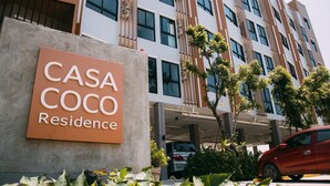 A modern building with a sign reading "CASA COCO Residence". - Casa Coco Hotel (Nakhon Ratchasima)