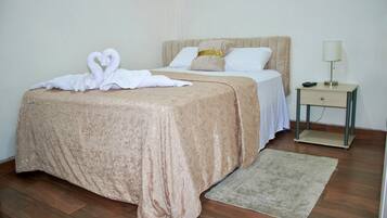 A neatly made bed with a decorative headboard, a bedside table with a lamp, and a rug on a wooden floor.
