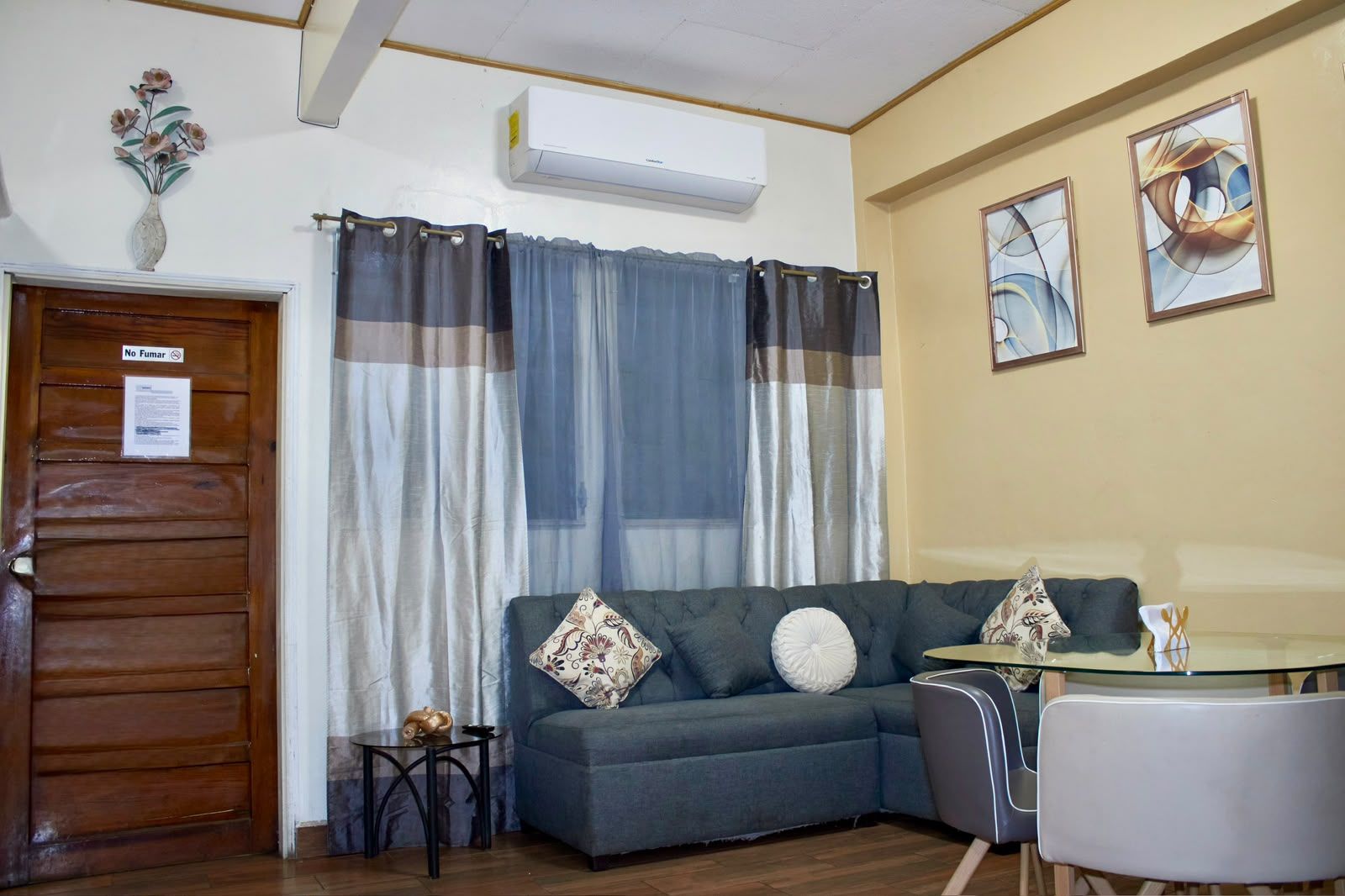 A living room with a sofa, a small table, a chair, and a window with curtains.