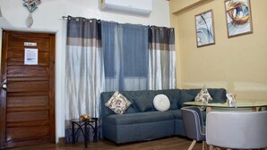 A living room with a sofa, a small table, a chair, and a window with curtains. - 2-bedroom apartment in welcoming Tegucigalpa with WiFi (Tegucigalpa)