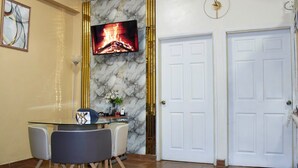 A dining area with a glass table, chairs, a television displaying a fireplace, and two white doors. - 2-bedroom apartment in welcoming Tegucigalpa with WiFi (Tegucigalpa)
