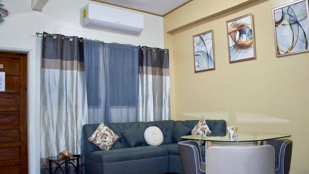 A room with a grey sofa, a glass table, and two chairs. There are three abstract paintings on the wall. - 2-bedroom apartment in welcoming Tegucigalpa with WiFi (Tegucigalpa)