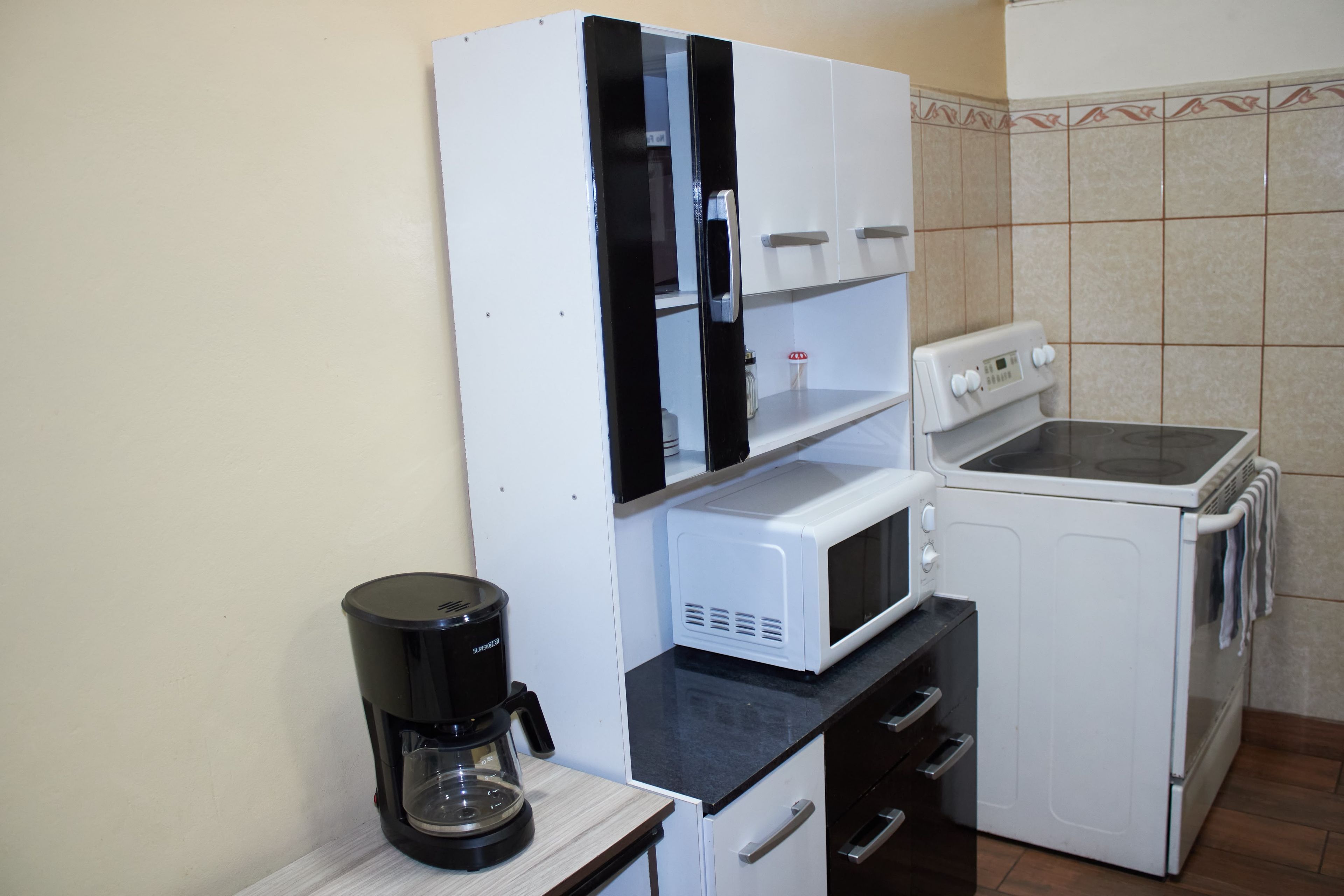 Eine kompakte Küche mit Kaffeemaschine, Mikrowelle und kleinem Backofen.