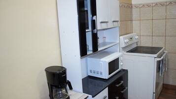 Eine kompakte Küche mit Kaffeemaschine, Mikrowelle und kleinem Backofen.