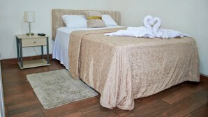 A neatly arranged bedroom with a bed, bedside table, lamp, and a decorative swan towel on the bed. - 2-bedroom apartment in welcoming Tegucigalpa with WiFi (Tegucigalpa)