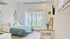 A bedroom with a bed, a desk, and a chair. There is a window with blinds, a mirror, and a vase with dried flowers on the desk. - La Ilusión, studio in Conil de la Fra. (Conil de la FRa.)