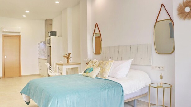 A bedroom with a bed, bedside tables, a desk, and a wardrobe. - La Ilusión IV, studio in Conil. (Conil de la Fra.)