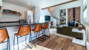 A modern kitchen with a central island, bar stools, and a dining area with a sofa and coffee table. - Sweet 1Bed/Loft/1Bath EagleVail (Avon)